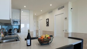 A modern kitchen with a stainless steel sink, a microwave, a wine bottle, and a fruit basket on the counter. - A UNIQUE PARADISE in Royal Beach, Mijas beach (Calahonda - Mijas Costa)