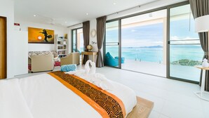 A spacious bedroom with a large bed, a view of the sea, a seating area with a table, and a bookshelf. - Luxury 5-bedroom villa with panoramic sea view (Koh Samui)