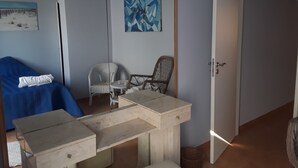 Ein Zimmer mit einem Bett, einem Schreibtisch, zwei Stühlen, einem Gemälde und einer Tür.