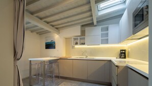 A compact kitchen with a white countertop, a stainless steel sink, and a built-in microwave.