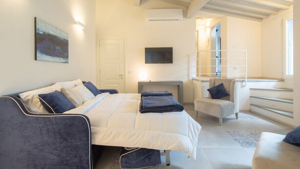 A bedroom with a bed, a chair, a desk, and a TV.