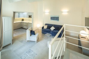 A modern living room with a sofa, a coffee table, and a kitchen area with a microwave. - Carapelli 7 Spectacular penthouse (florence)