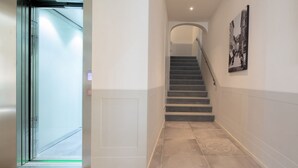 A hallway with a glass door, a staircase, and a framed picture on the wall.
