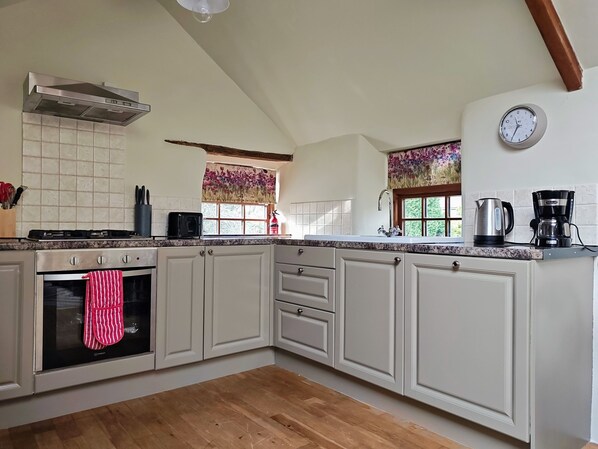 A kitchen with a stove, oven, and a window with floral curtains.