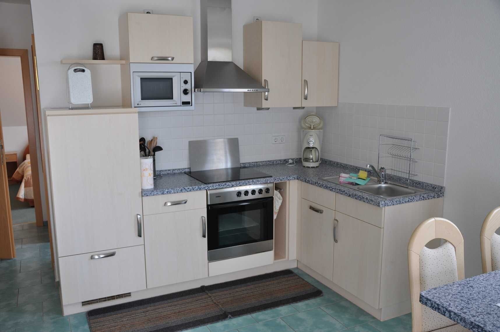 A compact kitchen with a microwave, stove, oven, and a coffee maker.