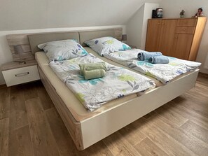 Ein Doppelbett mit Blumenbettwäsche, ein Holz-Kopfbrett, ein Nachttisch mit Lampe und ein Holzschrank.