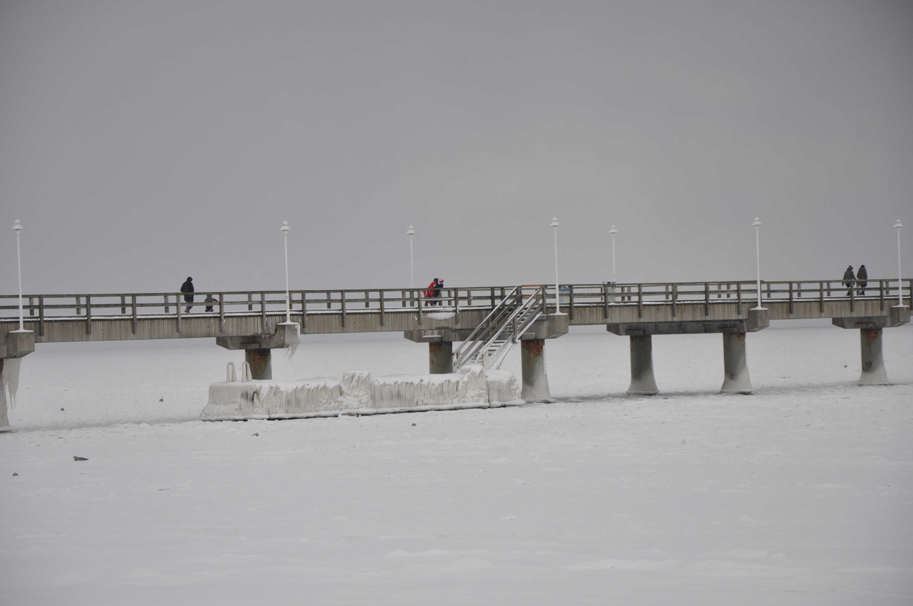 A bridge over a frozen body of water with people walking on it.