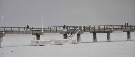 A bridge over a frozen body of water with people walking on it.