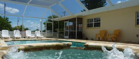A swimming pool with a glass enclosure, surrounded by lounge chairs and a covered patio area.