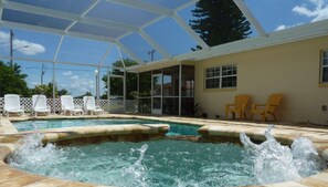 A swimming pool with a glass enclosure, surrounded by lounge chairs and a covered patio area.