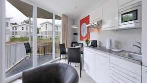 Una cocina moderna con comedor, ventanas amplias y vistas a edificios residenciales.
