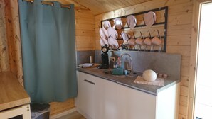 Een kleine keuken met een spoelbak, waterkoker en een wandplank voor borden.