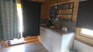 Een compacte keuken met een houten aanrechtblad, een spoelbak en een wandrek voor keukengerei.