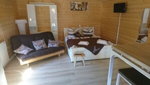 Een kamer met houten vloeren, een bed, een bank, een kleine tafel en een televisie.
