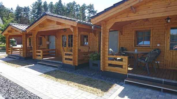 Een rij houten hutten met buitenzitjes en een kleine tafel.