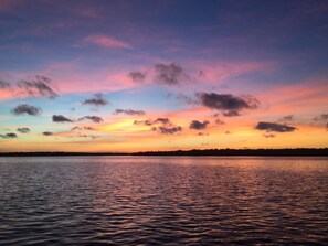 Une étendue d'eau calme qui reflète le ciel au coucher du soleil et les nuages.