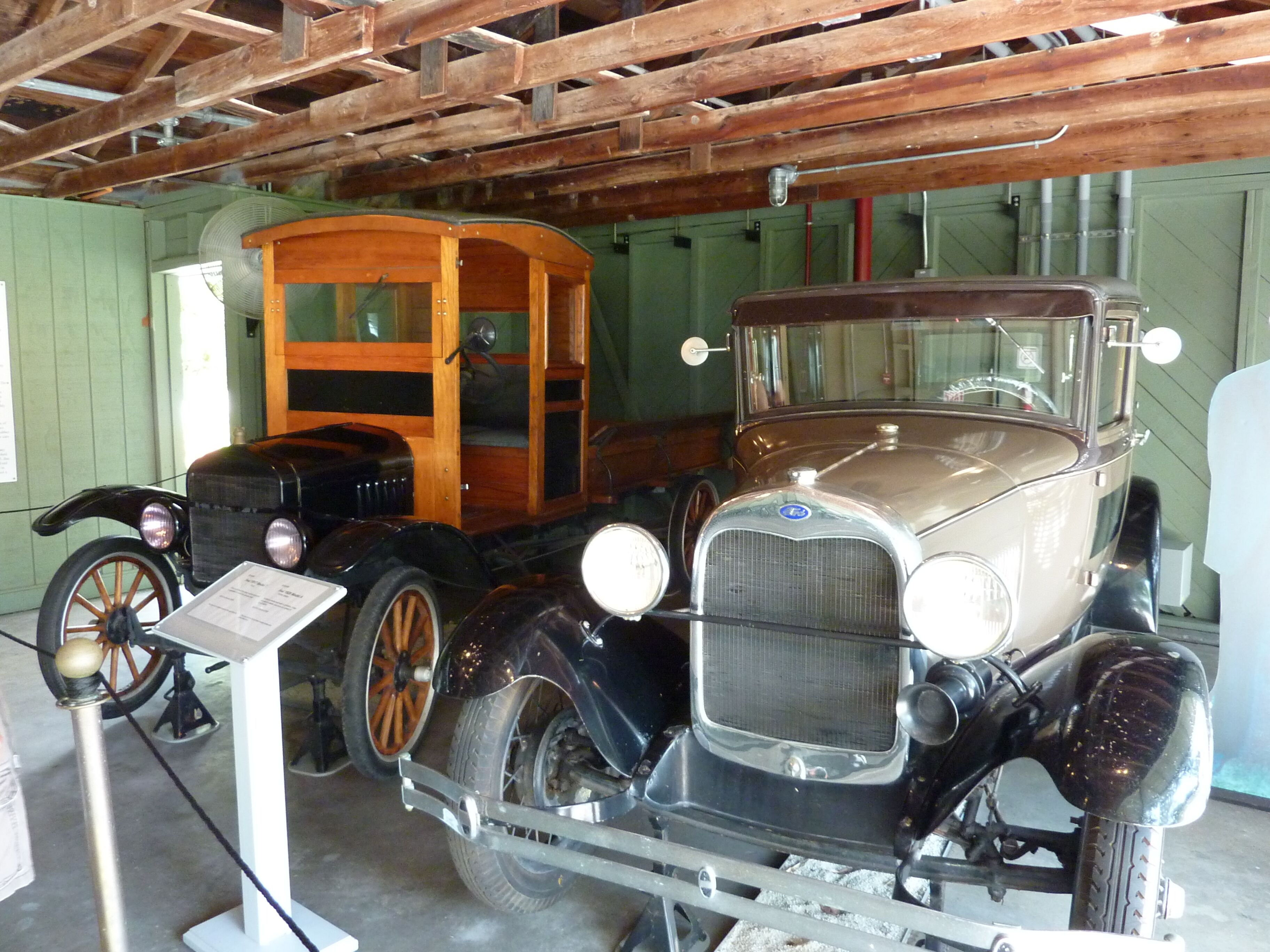 Une voiture ancienne exposée dans un musée, avec un intérieur en bois et une structure en métal.
