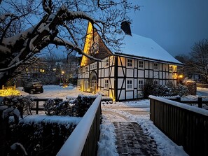 Ein traditionelles Fachwerkhäuschen mit verschneitem Dach und einem beleuchteten Turm.