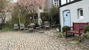 En innergård med stenbeläggning, utemöbler och en bänk.