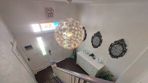 Un escalier avec une rampe blanche, un lustre décoratif et une commode blanche ornée de vases.