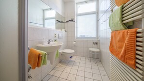 Kylpyhuone, jossa on pesuallas, wc ja ikkuna.