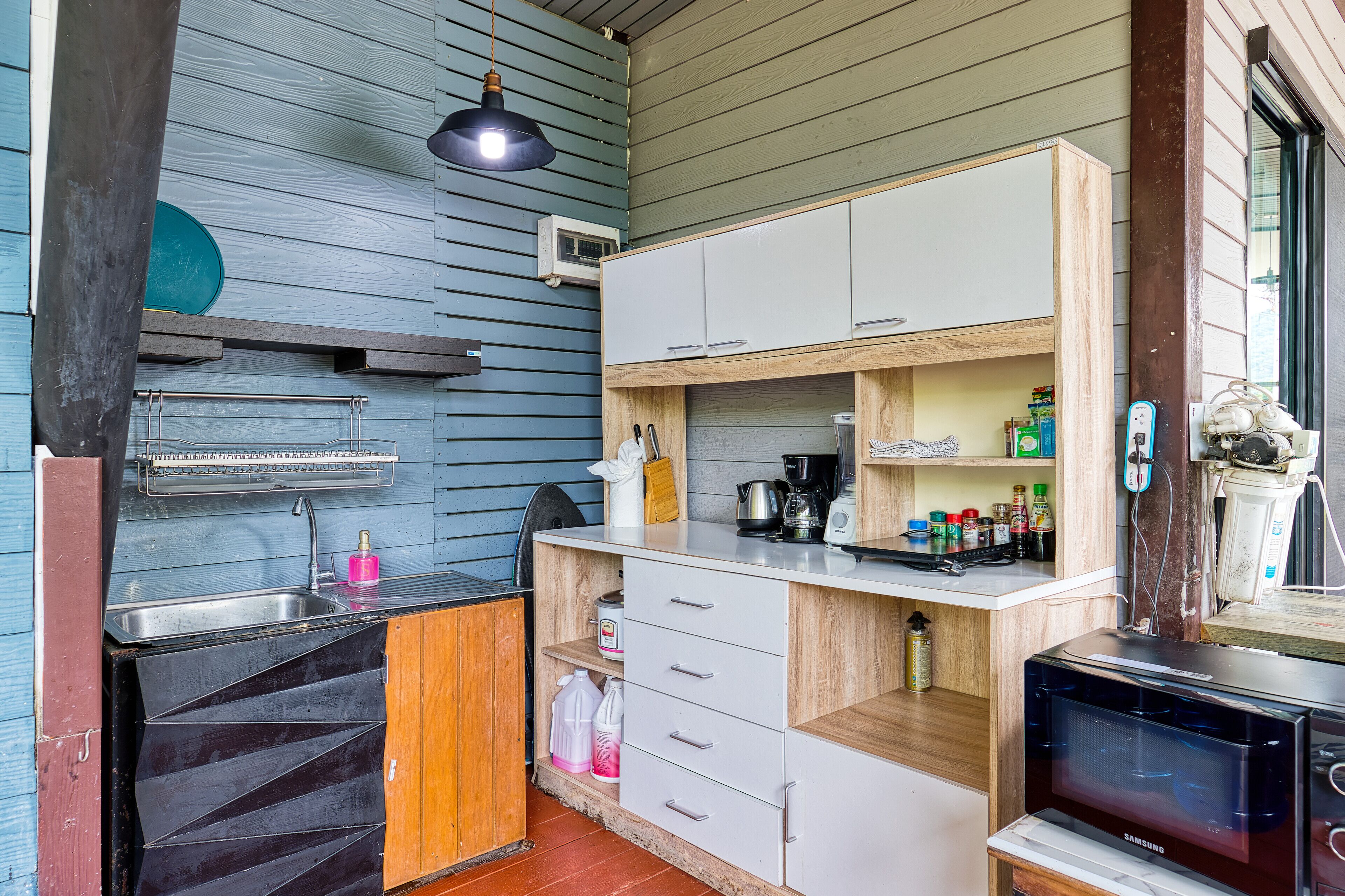 A compact kitchen with a sink, stove, microwave, and wooden cabinets.