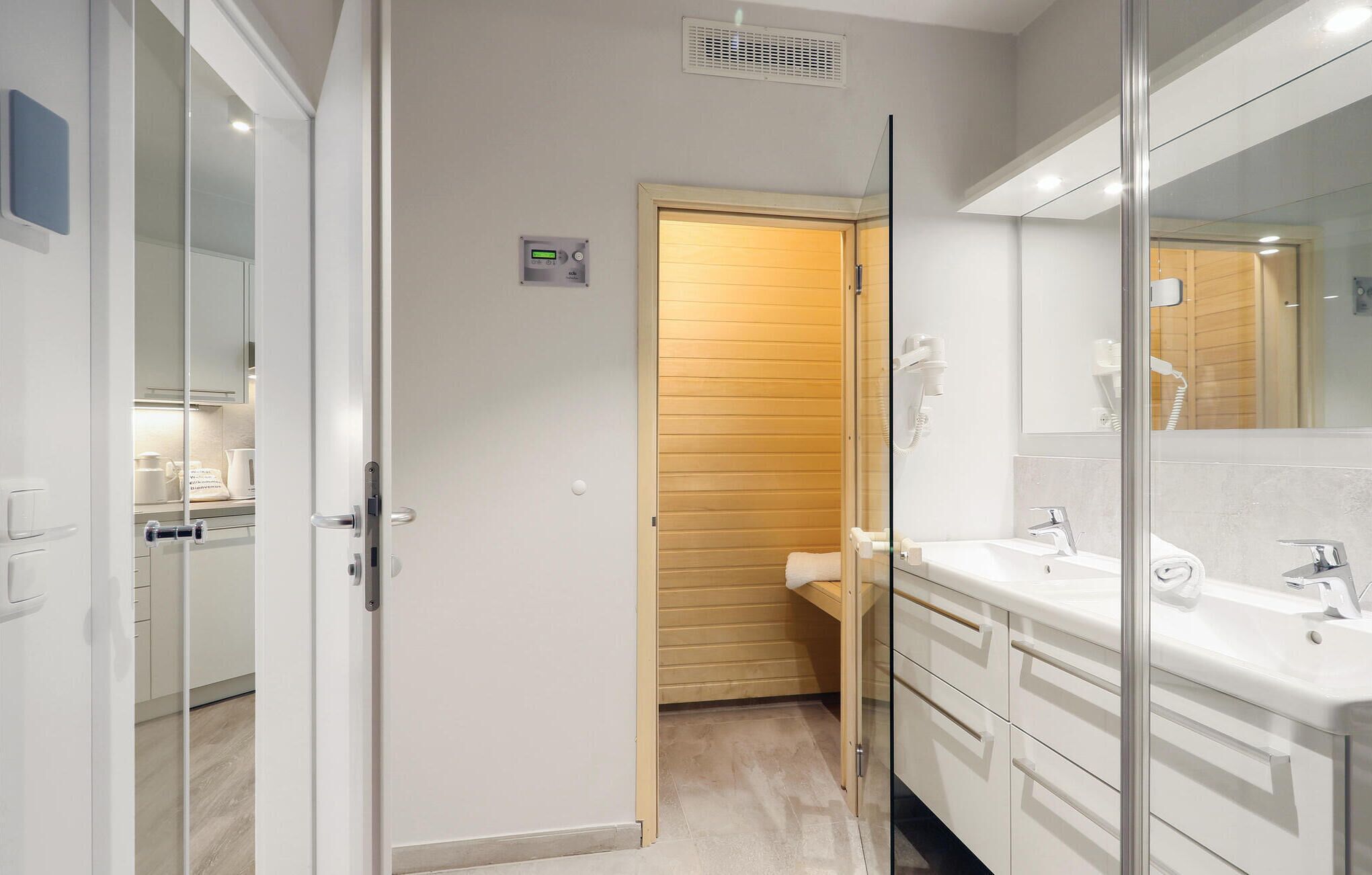 A modern bathroom with a large mirror, white cabinetry, and a shower area.