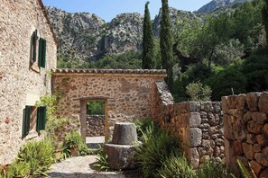 A rustic stone building with a narrow pathway, a stone wall, and a mountain backdrop. - FINCA TOMIR, private pool in an idyllic location, free  WLAN, max. 8 people (Pollença)