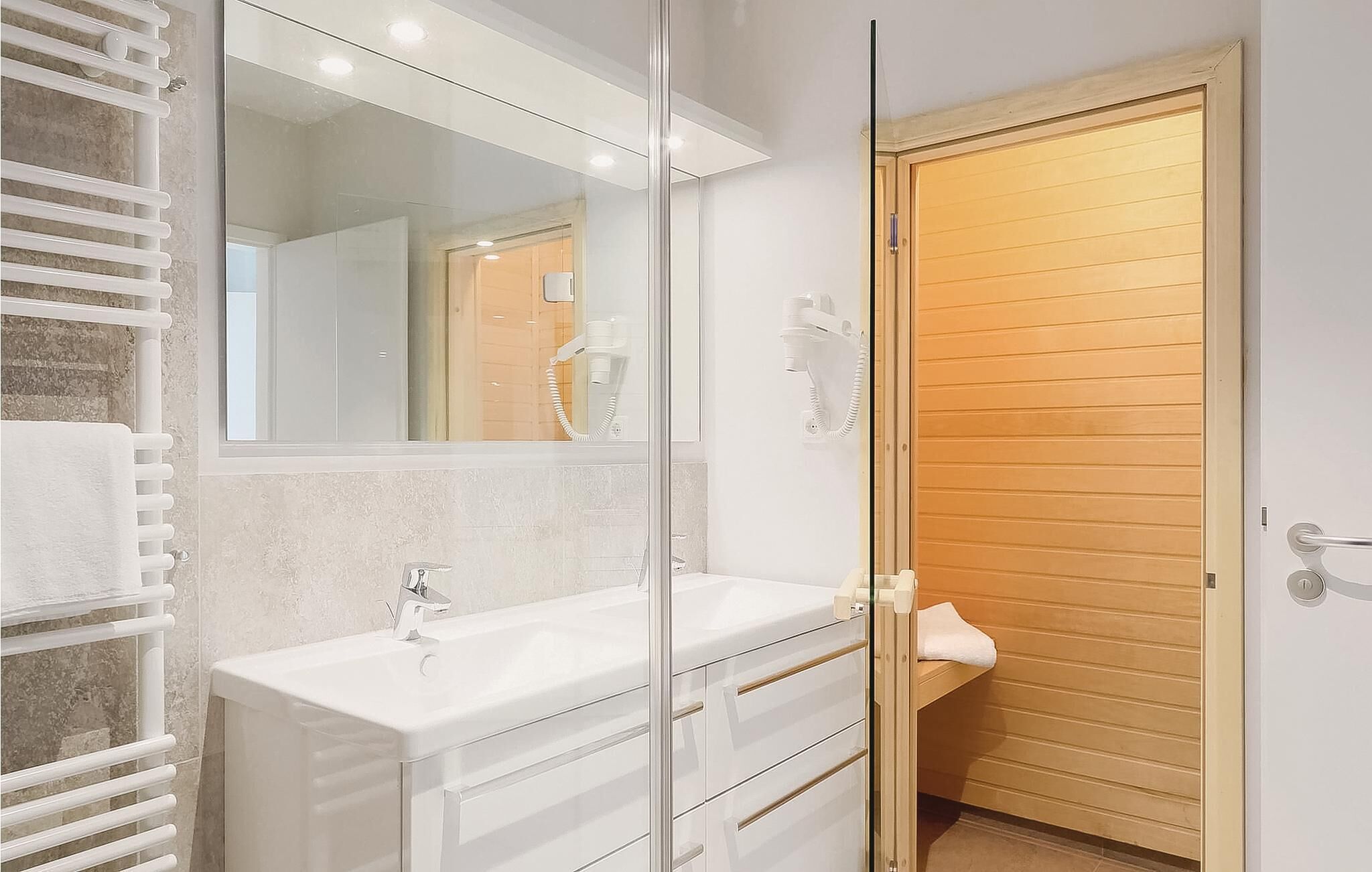 Une salle de bain moderne avec une douche à parois de verre, un lavabo blanc et une porte en bois.
