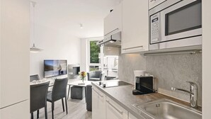 Une cuisine moderne avec un coin repas, des appareils en acier inoxydable et une vue sur l’extérieur.