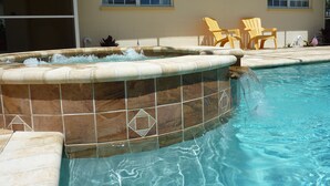 A swimming pool with a hot tub, tiled walls, and two yellow chairs. - Sun, beach, and great deals: Huge discounts on vacation destinations! (Cape Coral)
