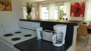 A kitchen with a stove, toaster, and coffee maker on a black countertop. - Sun, beach, and great deals: Huge discounts on vacation destinations! (Cape Coral)