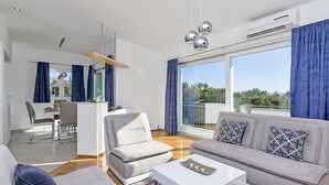 A modern living room with a sofa, a coffee table, and a dining area with a table and chairs. -  Holiday house with heated pool, terrace with sea view, 3 bedrooms, WiFi, BBQ (Bast)