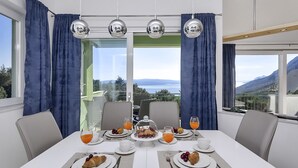 A dining area with a table set for breakfast, including croissants, fruit, and orange juice. -  Holiday house with heated pool, terrace with sea view, 3 bedrooms, WiFi, BBQ (Bast)