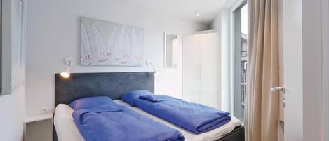 Un dormitorio moderno con una cama, cabecero, una obra de arte en la pared y un armario.