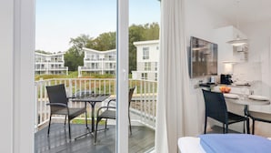 Une chambre d’hôtel moderne dotée d’un balcon, d’un coin repas et d’une télévision.