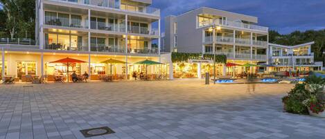 A multi-story hotel with outdoor seating areas and a covered walkway.
