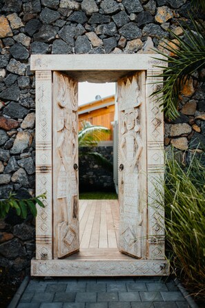 Une porte en bois sculptée, ornée de motifs complexes, qui se détache sur un mur de pierre.