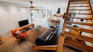 Un salon moderne avec un canapé, un téléviseur et un escalier en bois.