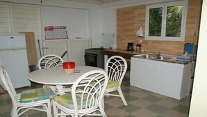 Una cocina compacta con una mesa, sillas, un refrigerador, una estufa y un lavabo.
