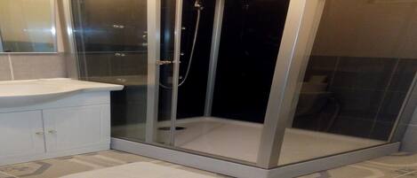 A bathroom with a glass-enclosed shower, a white sink, and a tiled floor.