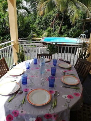 An outdoor dining area with a pool in the background. - Vacation complex consisting of three 3-bedroom houses, at <br>L' étage (Ste Anne)