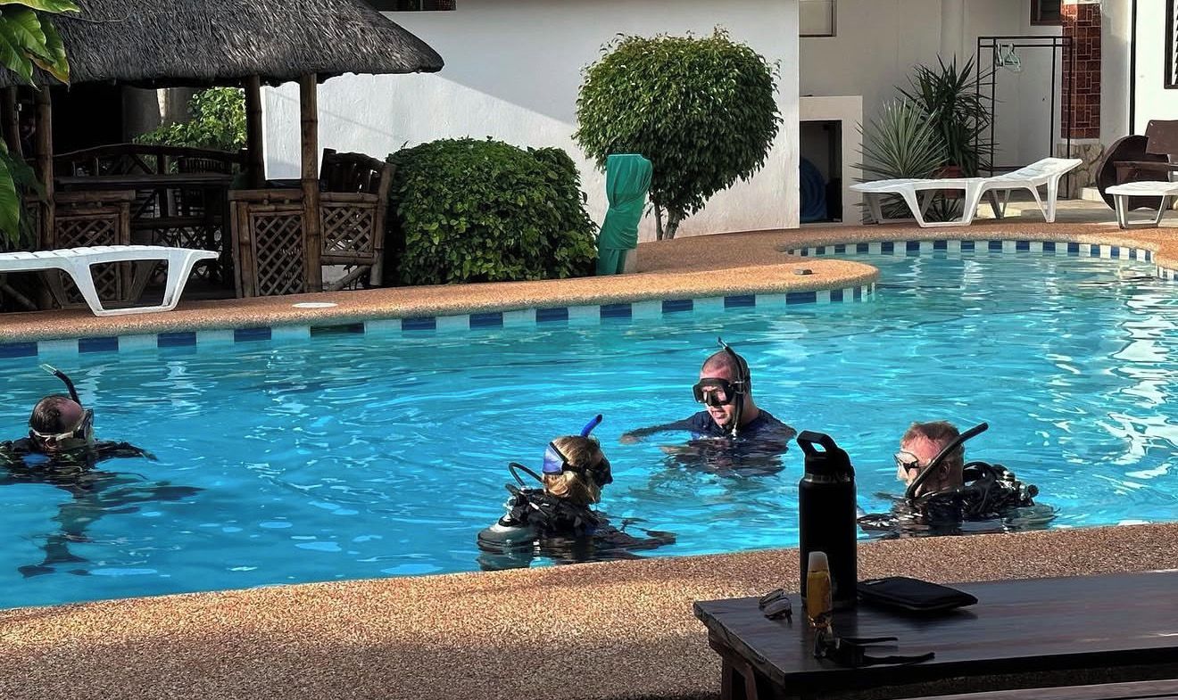A swimming pool with lounge chairs and a thatched roof structure.