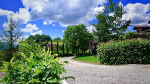 A gravel path leading to a house surrounded by lush greenery and trees. - Gites le Paradis *** Superb view of Vercors (Pont-en-Royans)