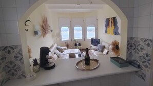 Een woonkamer met een bank, een salontafel, een televisie en een uitzicht door grote ramen.