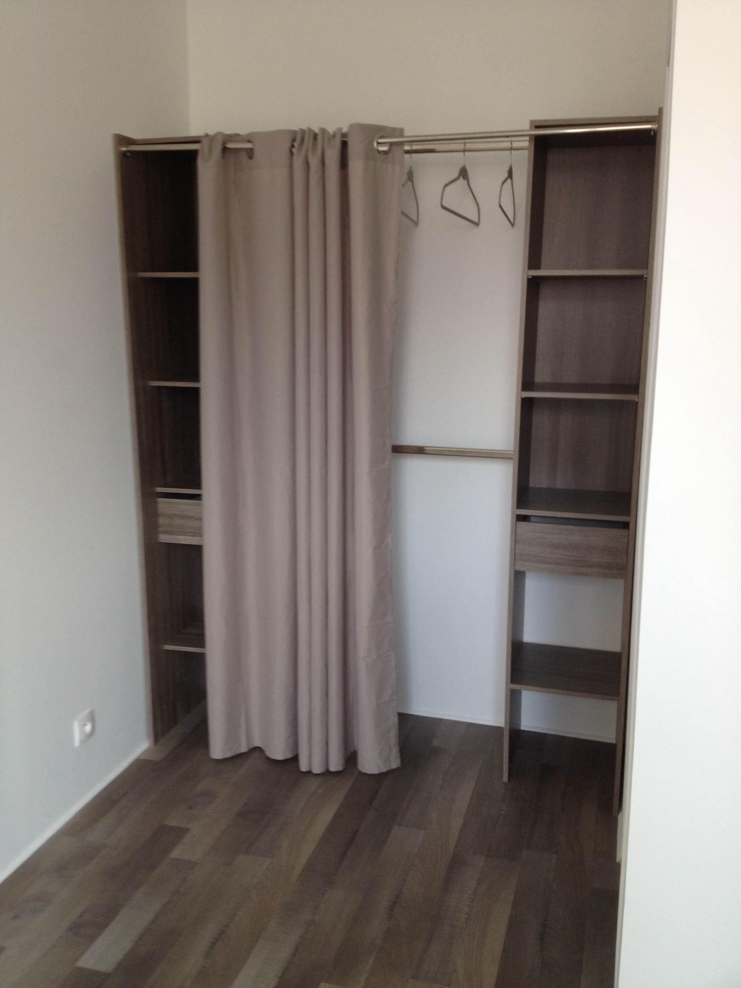 Un dressing avec des étagères en bois et une tringle pour suspendre les vêtements.