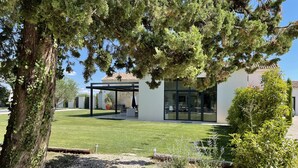 A modern house with a covered patio, a well-maintained lawn, and a gravel path. - Haven of peace in the vineyards (Violes)