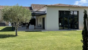 A modern house with a tiled roof, a covered patio, and a well-maintained lawn. - Haven of peace in the vineyards (Violes)