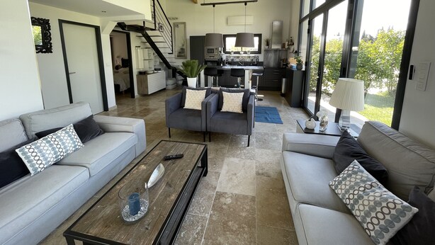 A spacious living area with a modern kitchen, a staircase leading to a bedroom, and large windows offering a view of the outdoors. - Haven of peace in the vineyards (Violes)