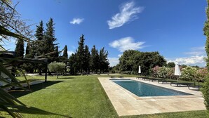 A rectangular swimming pool with a tiled deck, surrounded by a well-maintained lawn and tall trees. - Haven of peace in the vineyards (Violes)